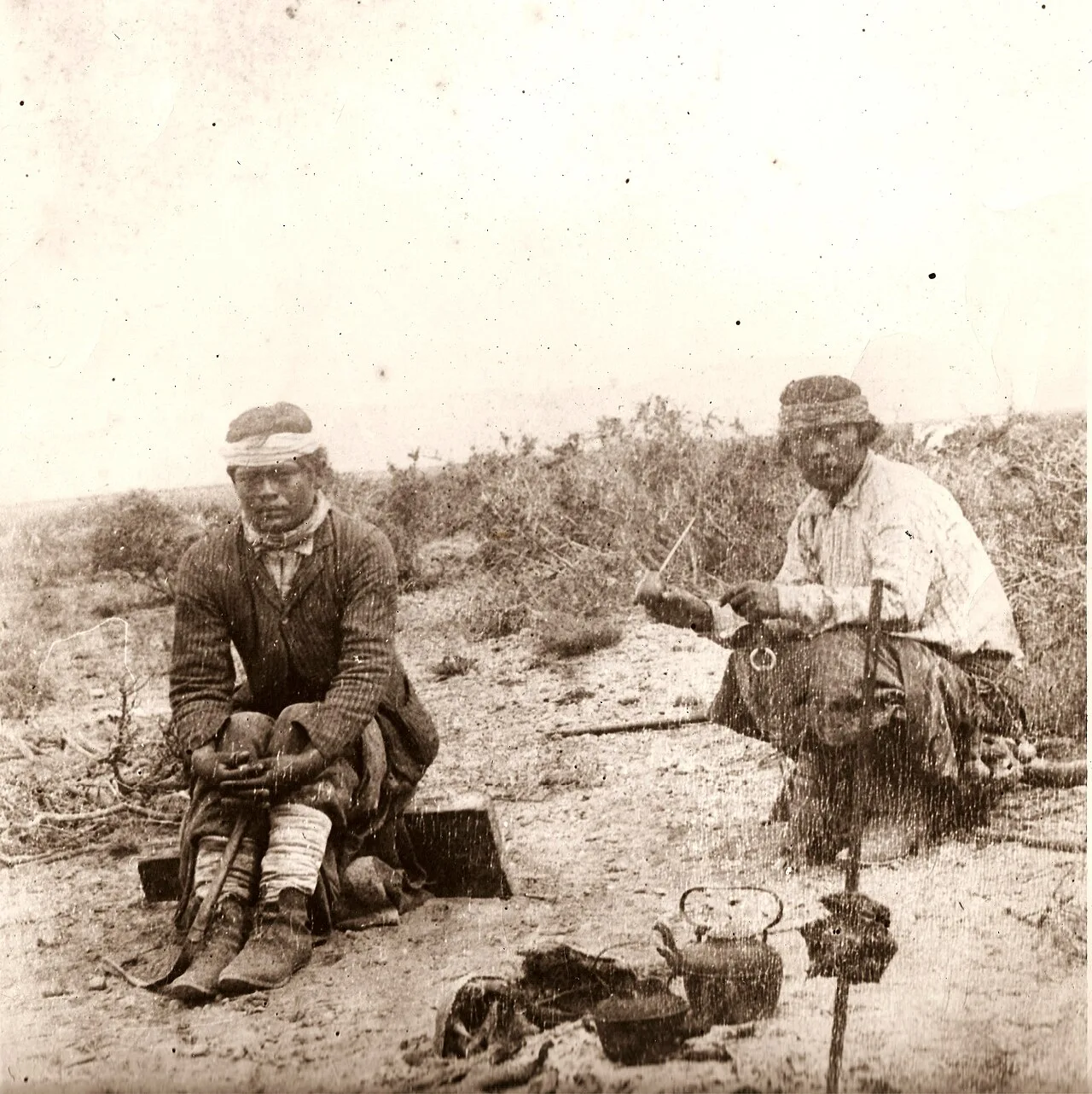 رجلان من المابوتشي يشربان المتّة في البامبا بينما يُطهى اللحم على النار أمامهما، نحو 1890.