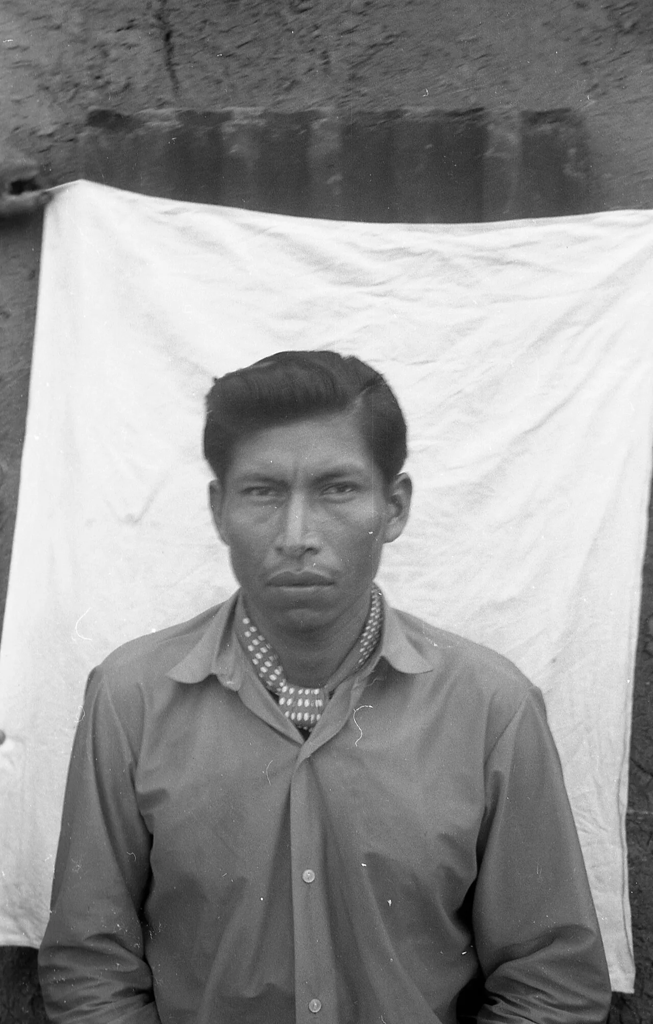 رجل من الكوم من سكان «حيّ التوبا» في ريسيستينسيا يقف أمام قطعة قماش بيضاء، 1968.