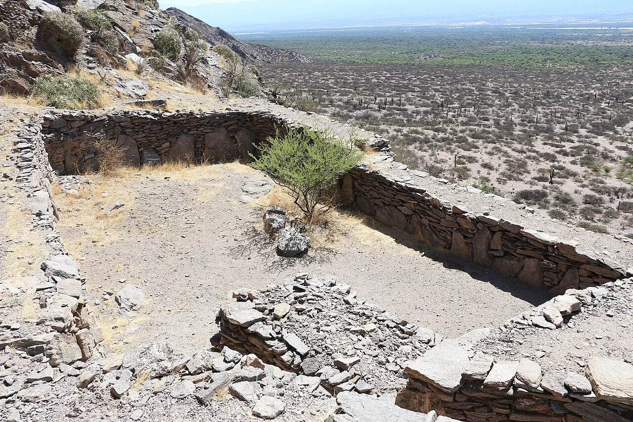 جدران حجرية لغرف مستطيلة على سفح الجبل في أطلال كيلمس، يطلّ منها الوادي الواسع، 2018.