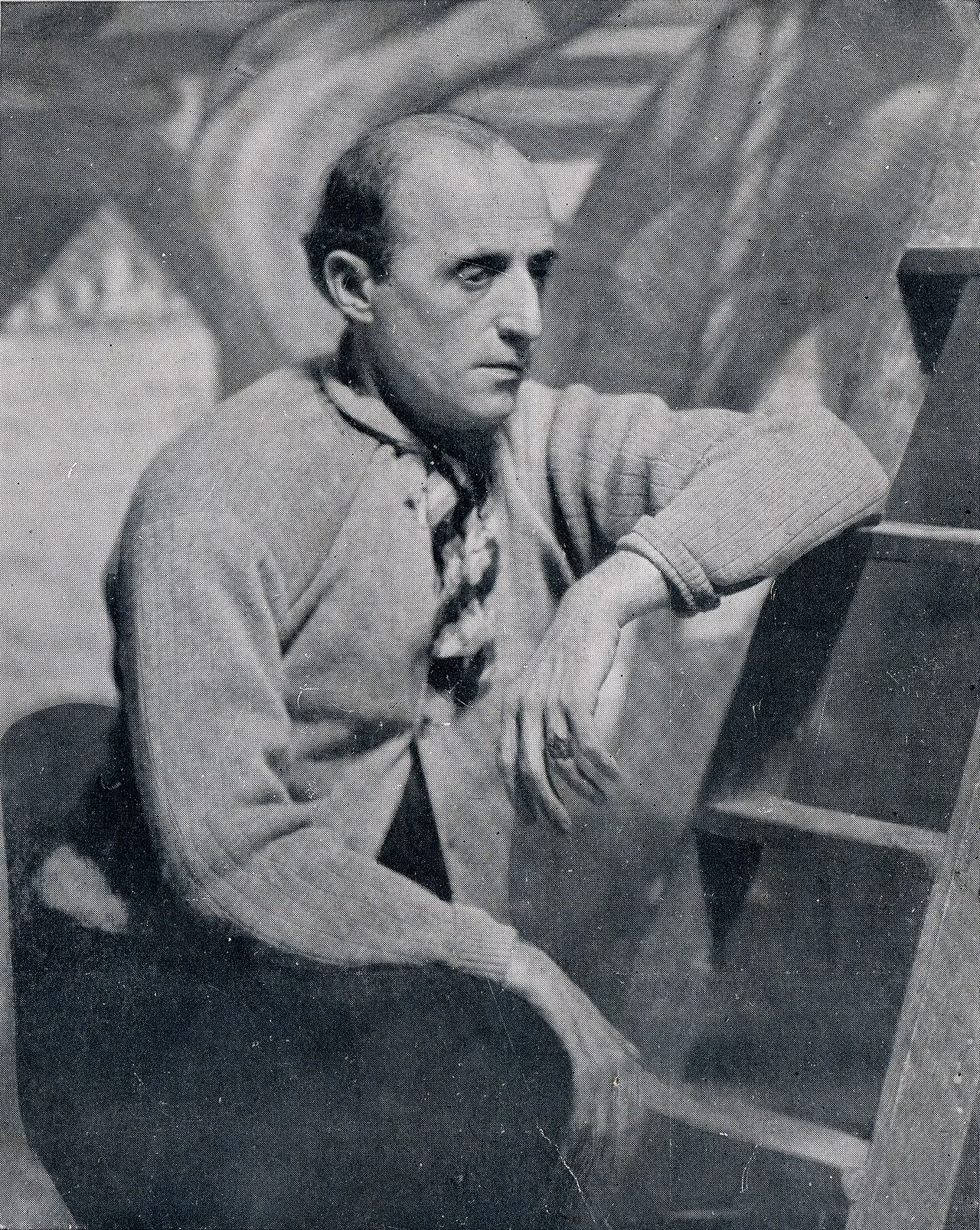 الرسام بينيتو كينكيلا مارتين جالساً في مرسمه متّكئاً بذراعه على قطعة خشبية، 1933